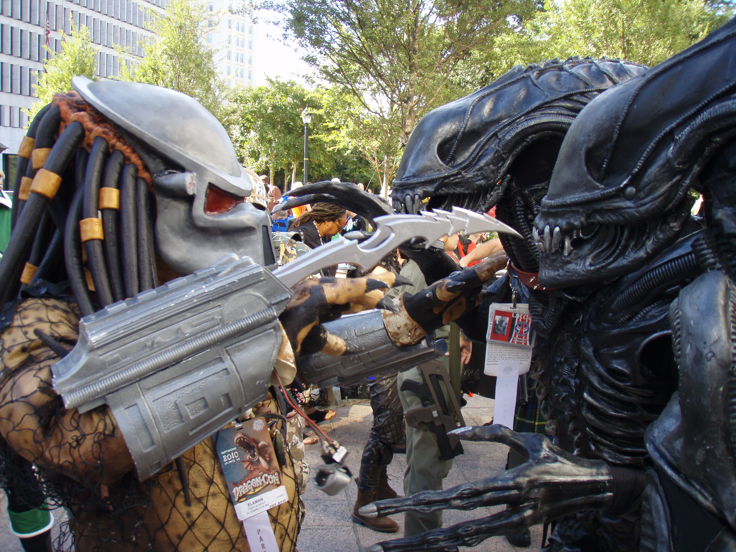 Two Alien Xenomorph costumes facing a Predator costume at Dragon Con 2010
